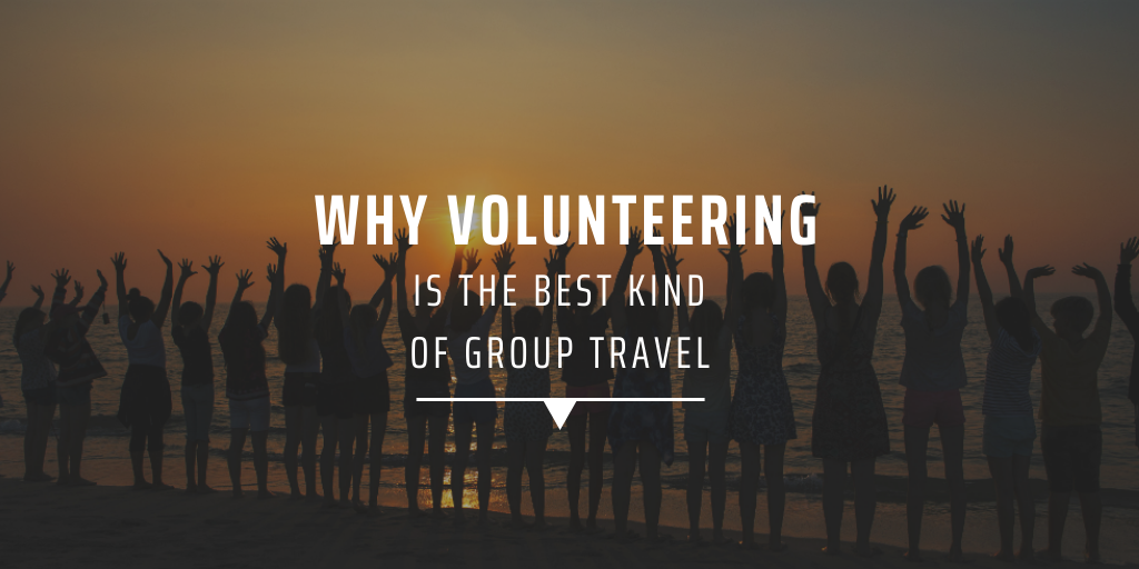 A group of volunteers standing on the beach with their arms raised.